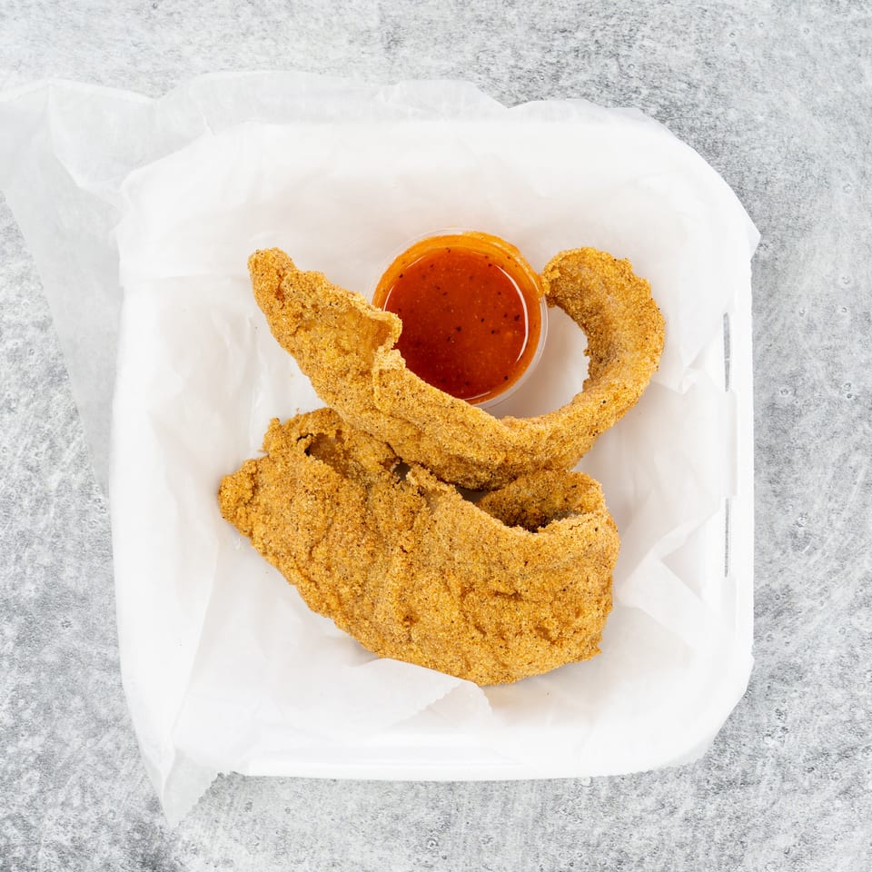 Two pieces of fried catfish with dipping sauce